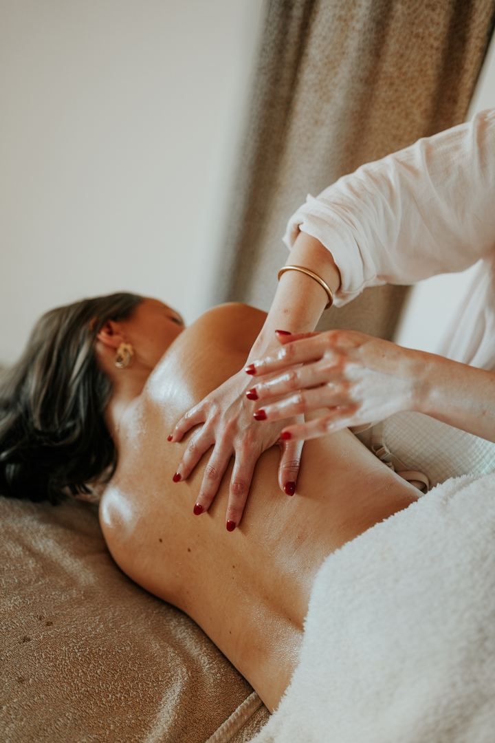 Un massage du dos à l'huile, les mains de la praticienne posées sur la peau